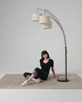 Bronze three arm lamp on a woven rug, a seated figure below the shades