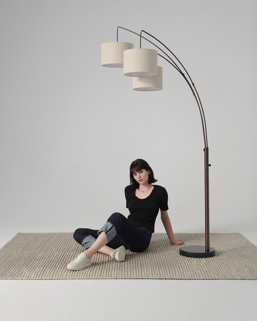 Bronze three arm lamp on a woven rug, a seated figure below the shades