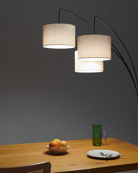 The three shades lit above a wood dining table with oranges and a glass
