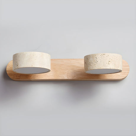 Two travertine discs set into a curved wood bar, seen unlit against a pale ground