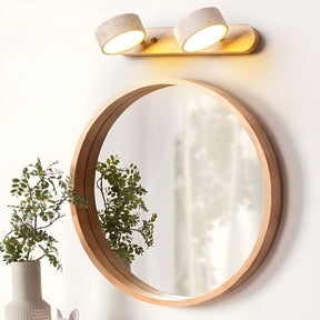 Two discs lit above a round wood framed mirror beside a branch in a vase