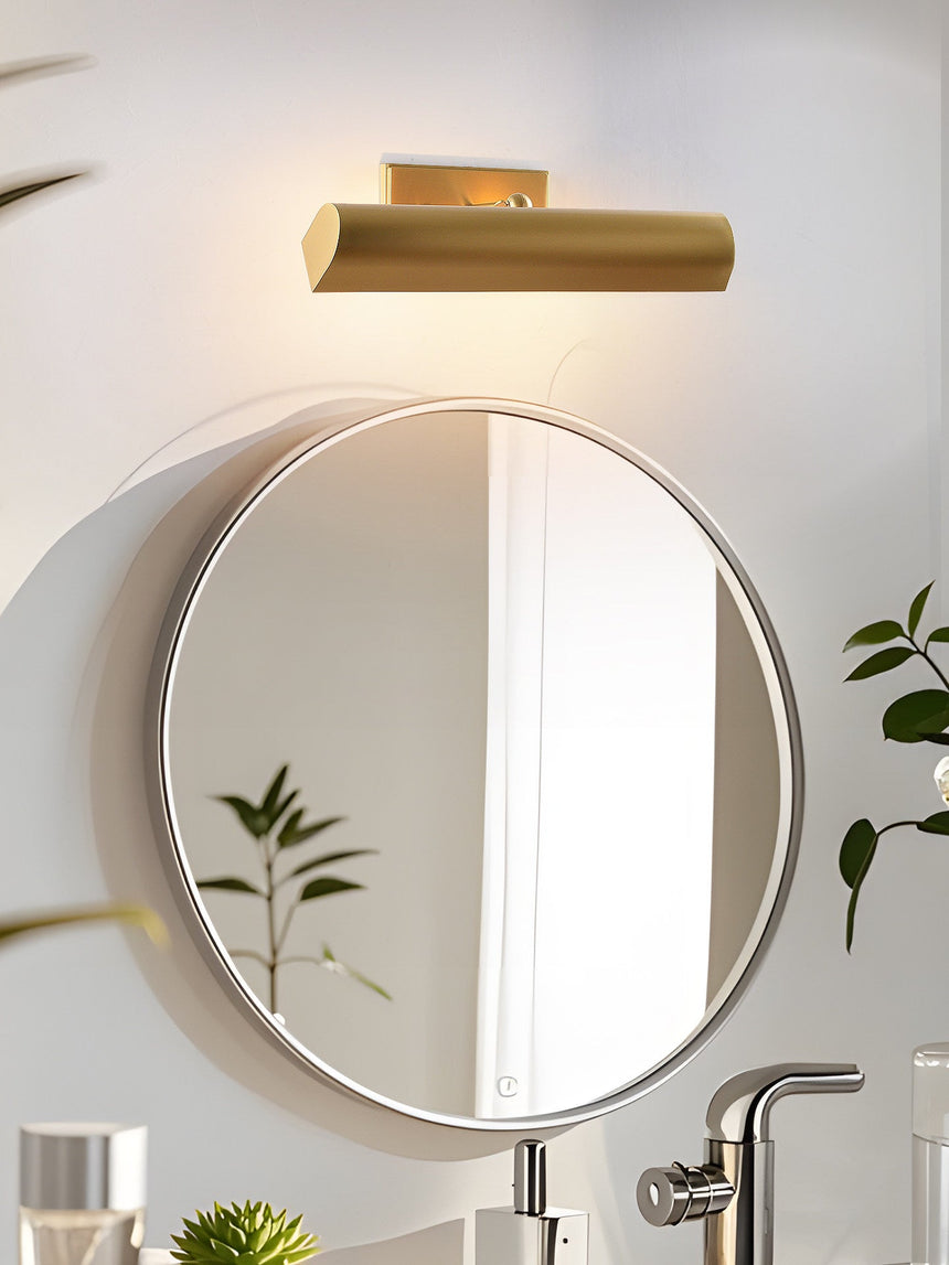Brass shade above a round mirror over a basin with a tap and a plant