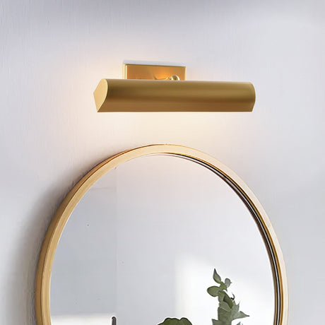 Brass shade above a round mirror, the glow spreading across the wall