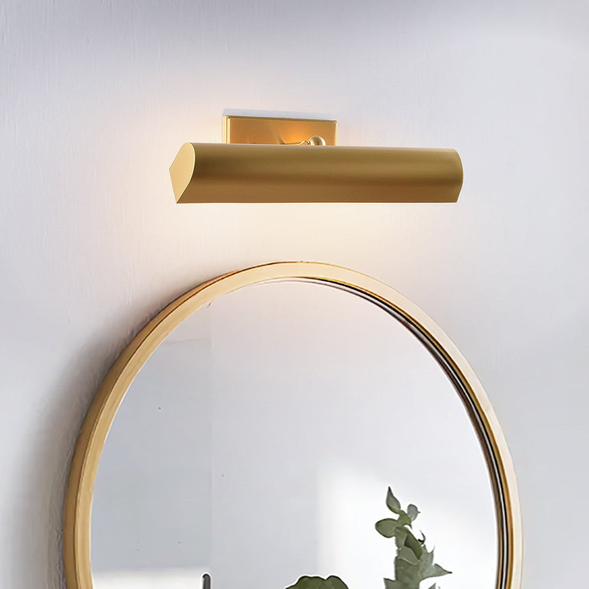 Brass shade above a round mirror, the glow spreading across the wall