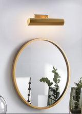 Brass shade above a round mirror with green glass vases beside the basin