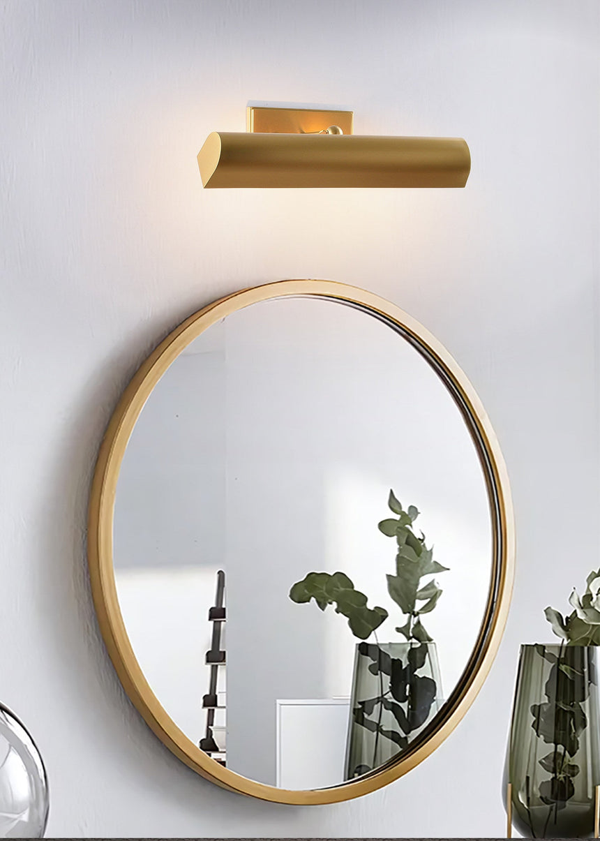 Brass shade above a round mirror with green glass vases beside the basin