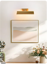 Brass shade lit over a framed print above a console with flowers