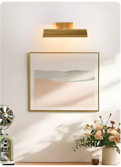 Brass shade lit over a framed print above a console with flowers