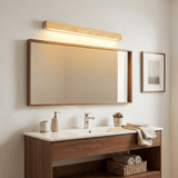 Wood bar lit above a framed mirror over a wall hung basin with folded towels