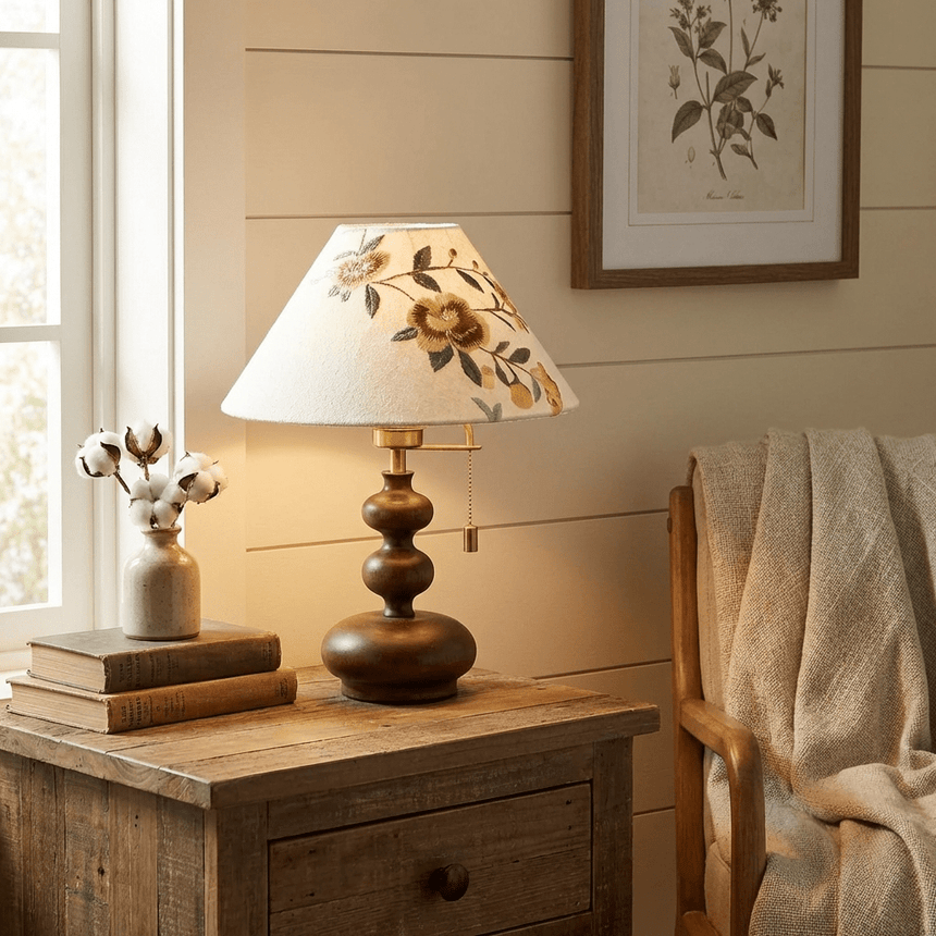 Floral shade lamp lit on a painted nightstand beside stacked books