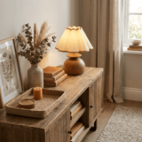 Accent table lamp lit on a rustic sideboard beside dried stems
