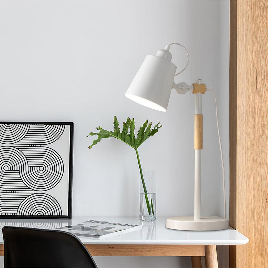 Adjustable desk lamp lit on a desk beside a black chair and a plant