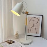 Adjustable desk lamp lit beside a framed line drawing and a magazine