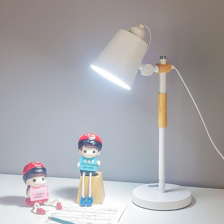 Adjustable desk lamp lit on a desk beside a framed print and toys
