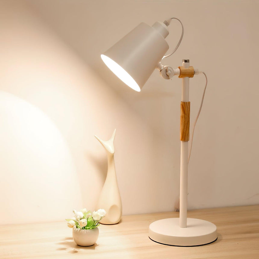 Adjustable desk lamp lit on a pale wooden desk beside a small figure