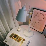 Adjustable desk lamp lit over an open magazine on a round table
