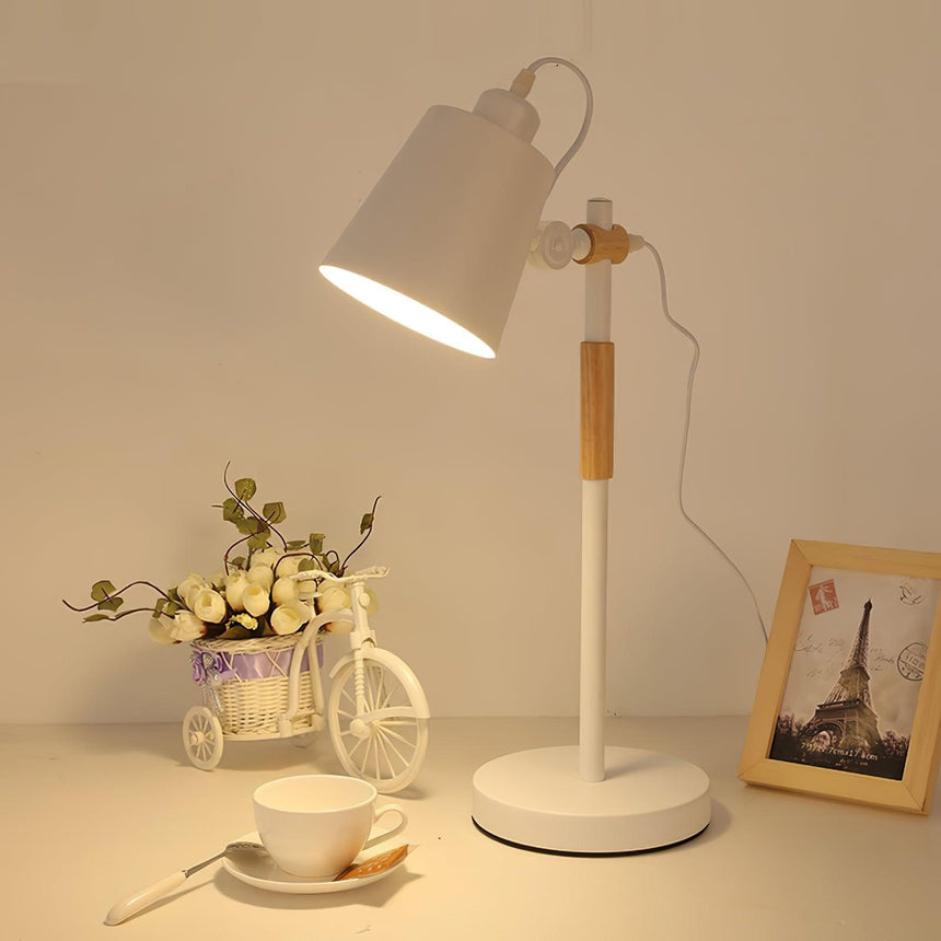 Adjustable desk lamp lit on a desk beside a small basket of flowers