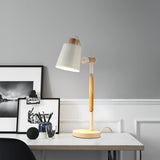 Adjustable desk lamp lit on a white desk beside framed pictures