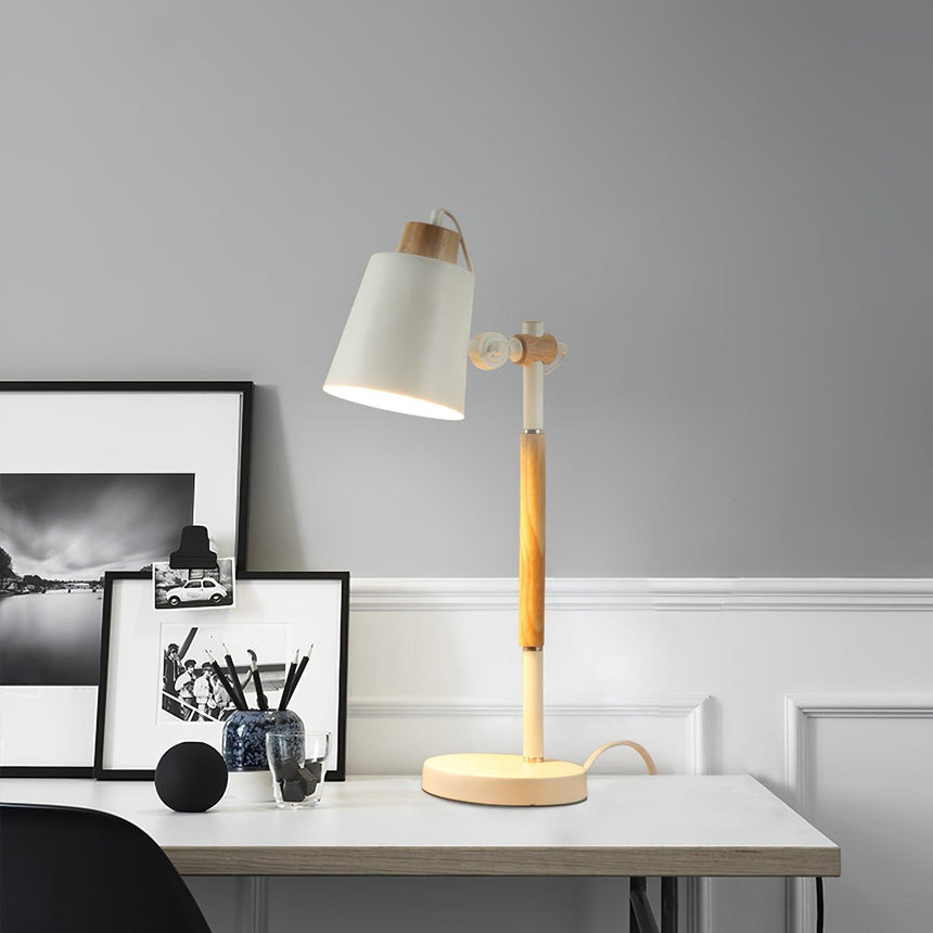 Adjustable desk lamp lit on a white desk beside framed pictures