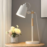 Adjustable desk lamp lit on a round table beside a vase of white roses