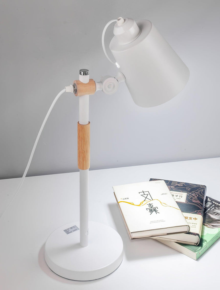 Adjustable desk lamp on a white surface beside two stacked books