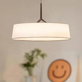 Flat drum shade lit above a table with a small vase
