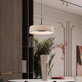 Flat cream drum shade hung above a console with a plant