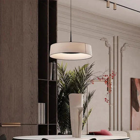 Flat cream drum shade hung above a console with a plant
