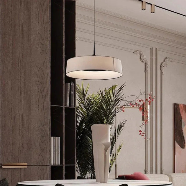 Flat cream drum shade hung above a console with a plant