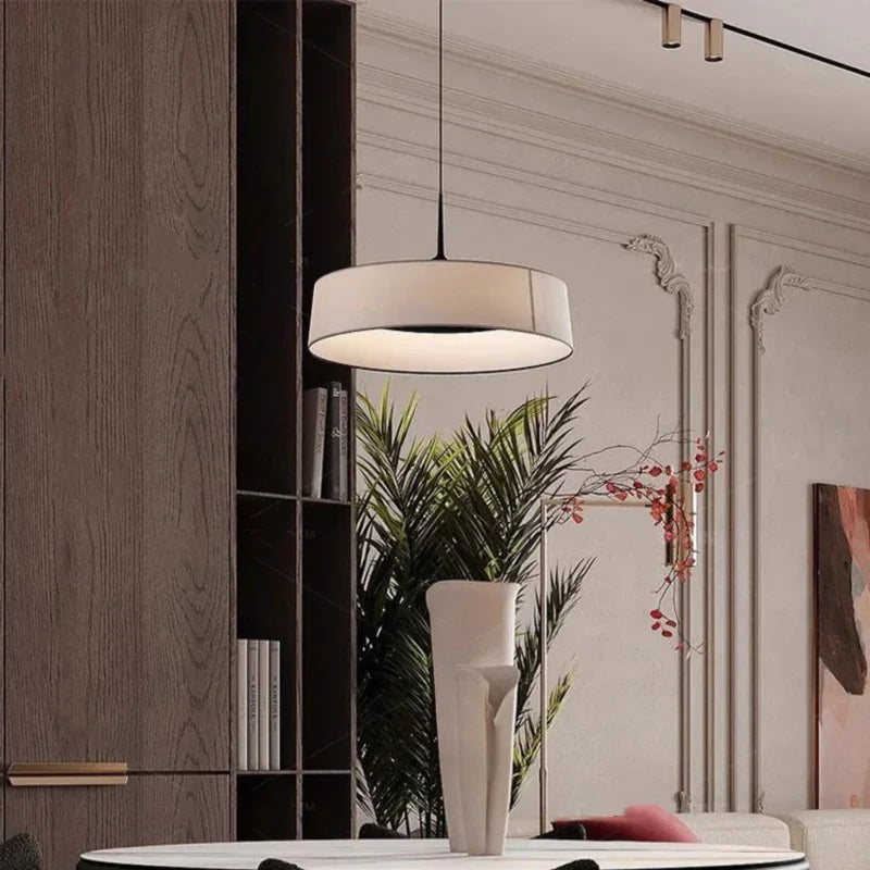 Flat cream drum shade hung above a console with a plant