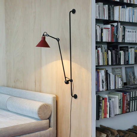 A red shade lamp beside a bookcase above a daybed with a bolster