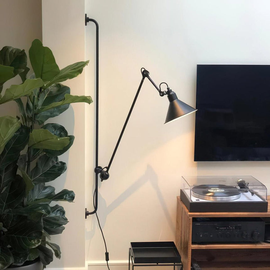 The lamp above a record player and a plant in a living room corner
