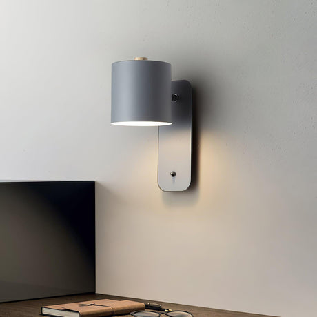 Mounted above a desk beside a monitor with books stacked on the surface below