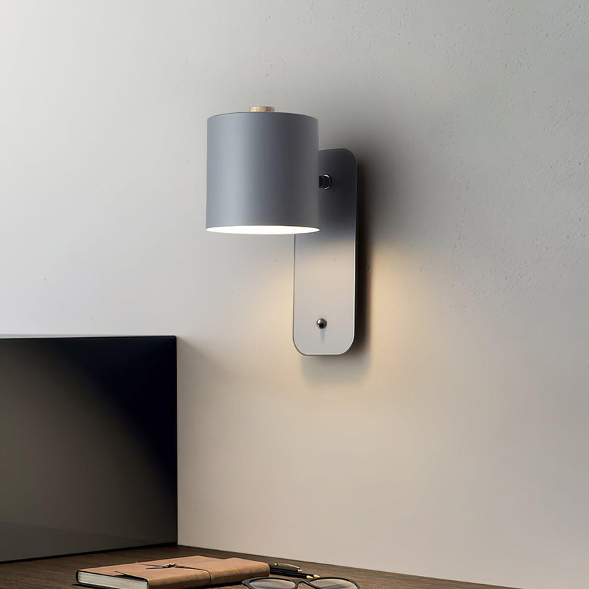 Mounted above a desk beside a monitor with books stacked on the surface below