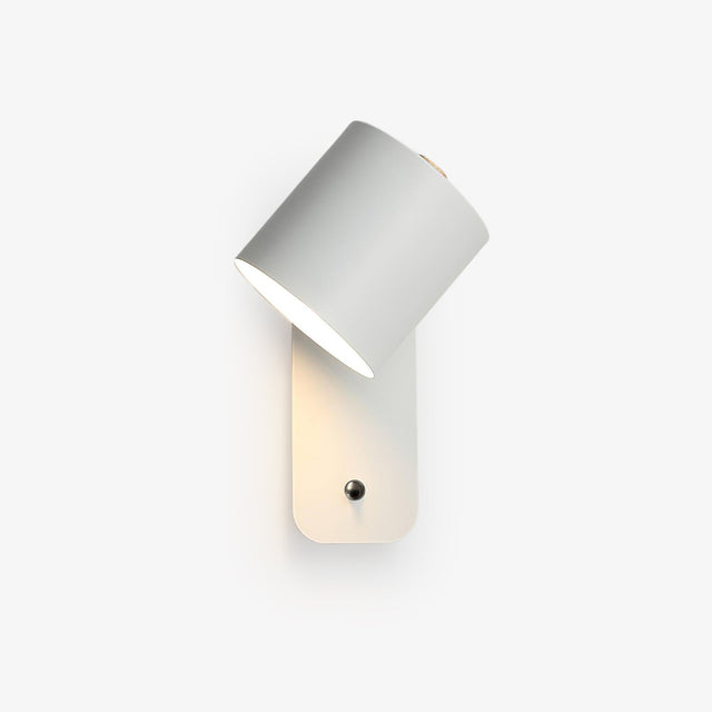 A white cylinder head tilted down on a rounded wall plate with a push button