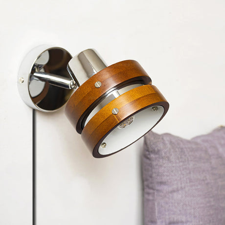 Sconce lit beside a bed with a purple pillow and a pale wall