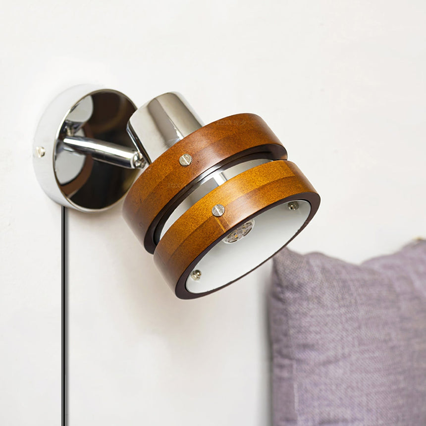 Sconce lit beside a bed with a purple pillow and a pale wall
