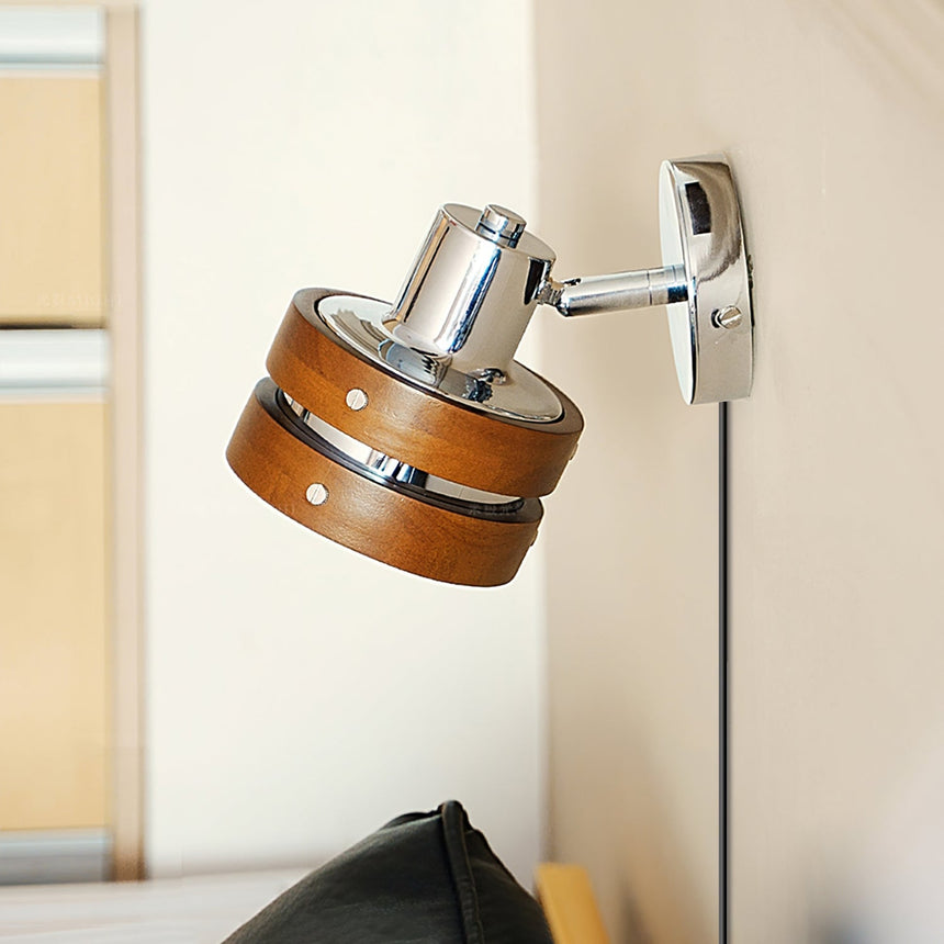 Sconce mounted in a corner above a dark chair, head turned out