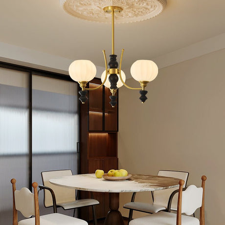 Chandelier lit above a round table with cane back chairs around it