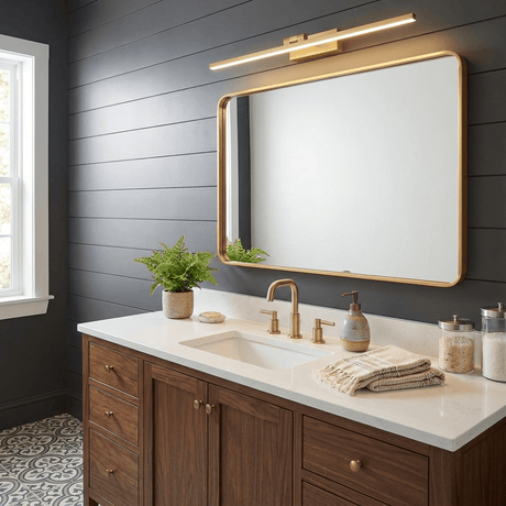Brass bar lit above a framed mirror on a dark panel wall over a walnut vanity