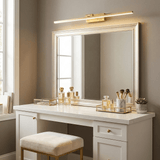 Brass bar lit above a framed mirror on a white dressing table with a gold tray