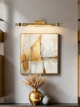 Ornate brass bar lit above a framed canvas over a tall gold vase