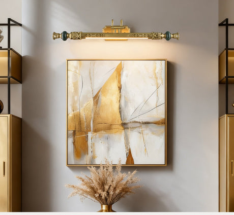 Ornate brass bar lit over a framed canvas above a vase of dried pampas