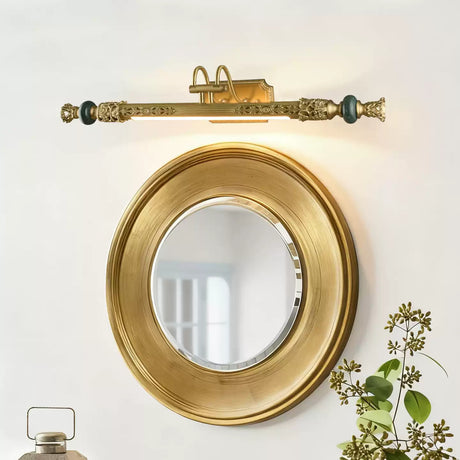 Ornate brass bar lit above a round gilt convex mirror with foliage beside it
