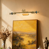 Ornate brass bar lit over a gilt framed landscape beside a small statue