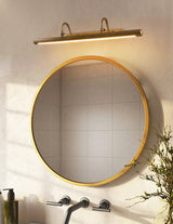 Brass bar lit above a round mirror over a wall mounted tap and a tiled basin