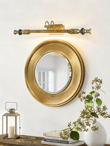 Ornate brass bar above a gilt mirror over books and a glass lantern