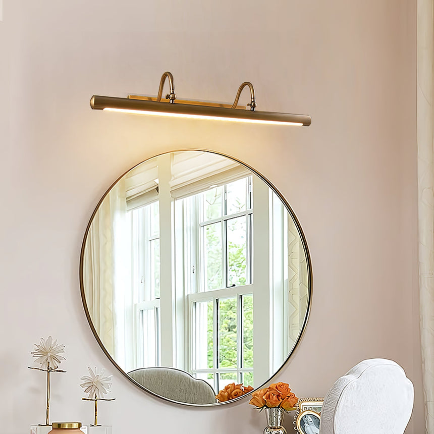 Brass bar lit above a round mirror reflecting a window, with flowers on a table