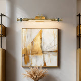Ornate brass bar lit above a framed abstract canvas on a pale wall