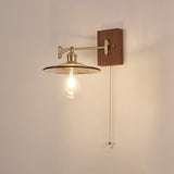 Clear glass disc lit with a visible filament lamp under a brass arm